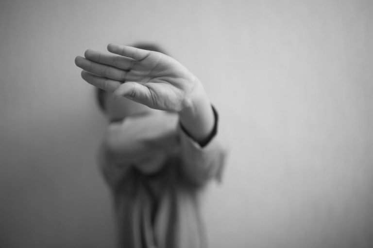 A little girl protects herself with her palm and covers her face