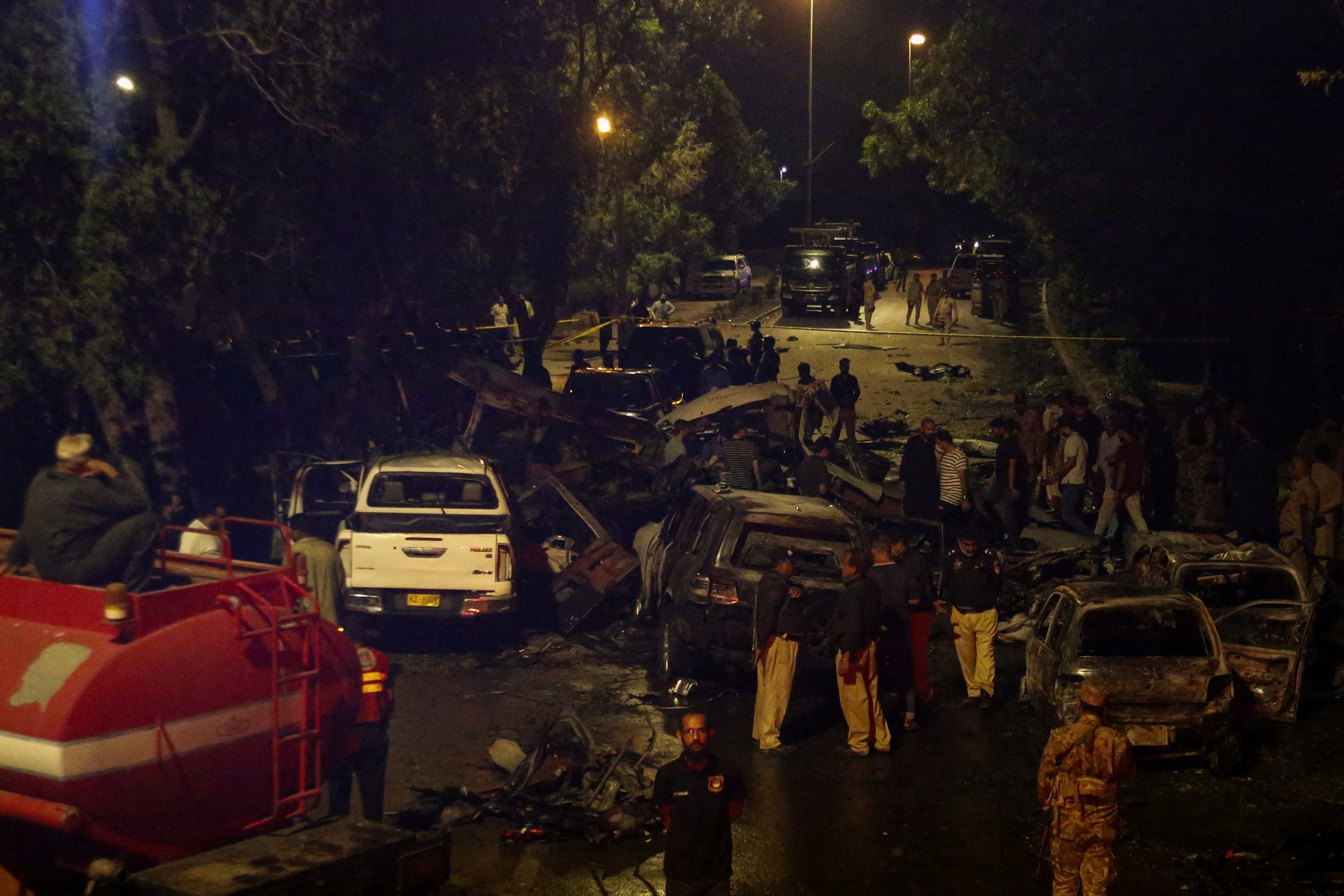 Police officers and paramilitary soldiers gather near the wreckage of vehicles after an explosion near Jinnah International Airport in Karachi